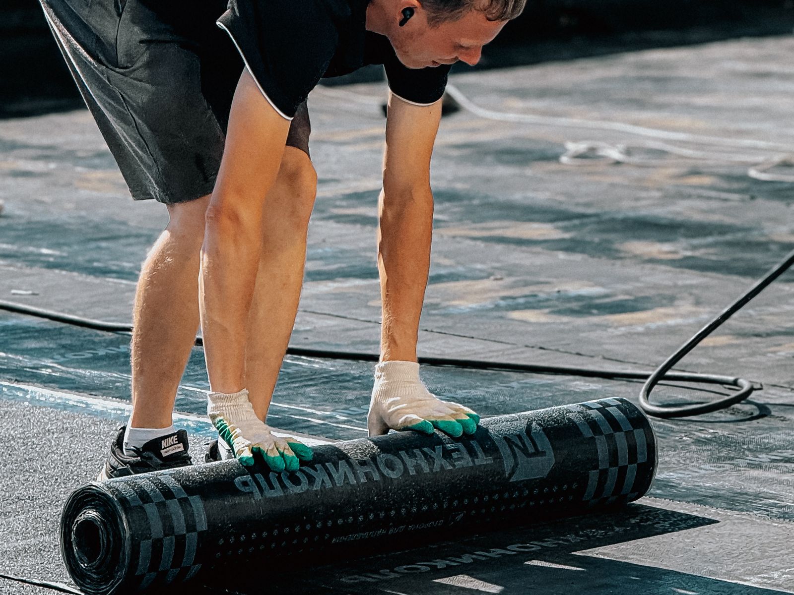 Dakdekker rolt een rol bitumen dakbedekking uit op een plat dak