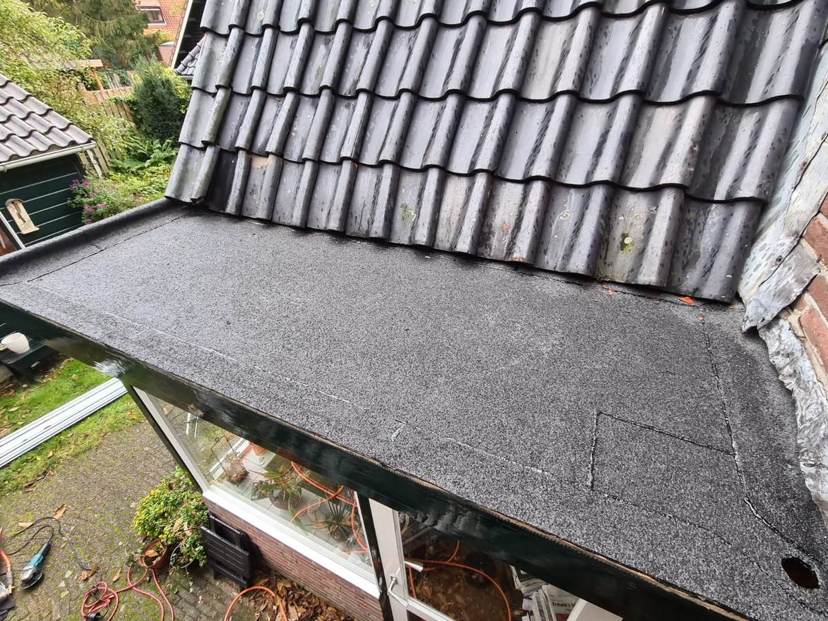 Nieuwe bitumen op plat dak naast een pannendak in Ermelo